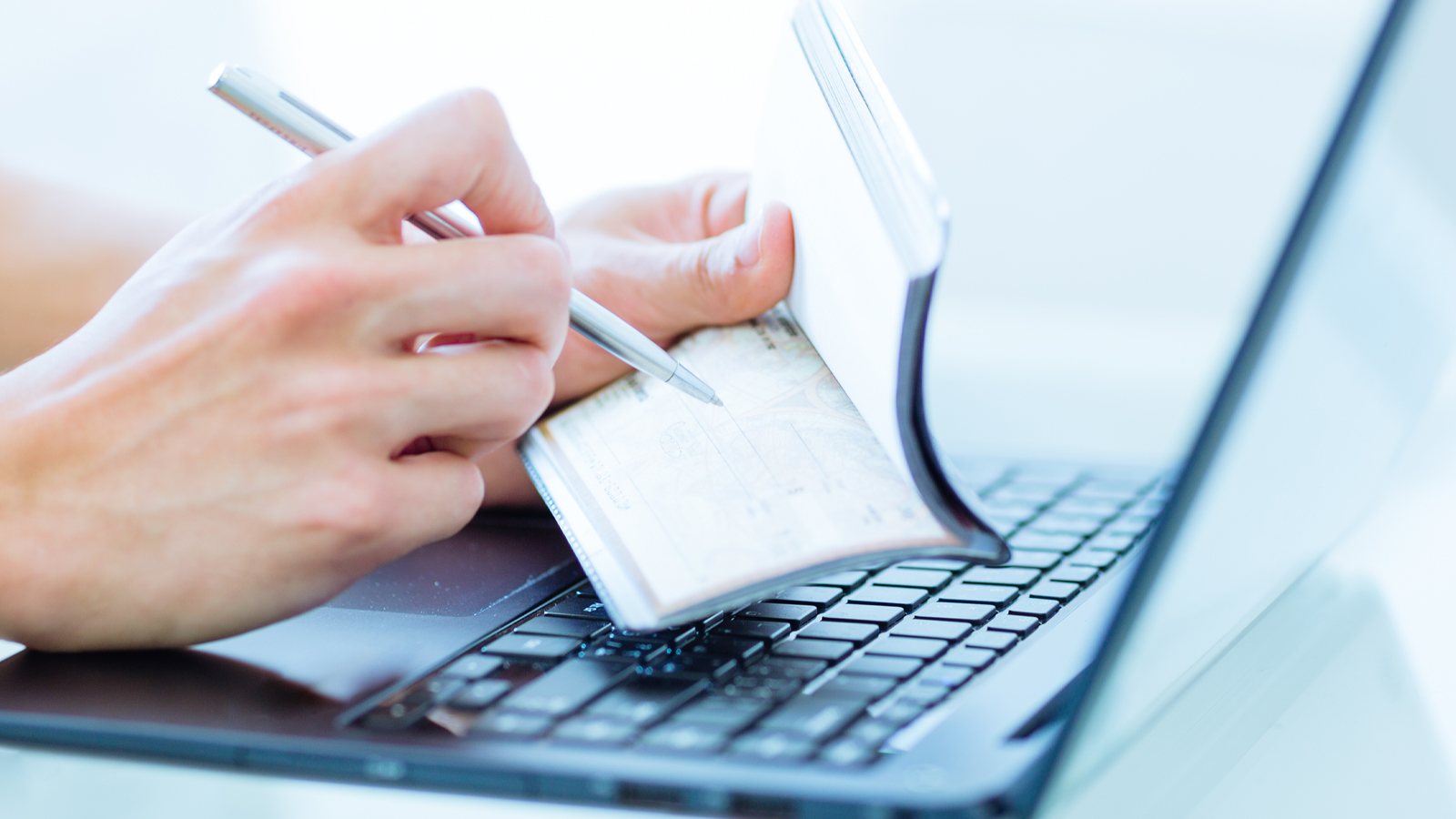 person on a laptop writing a check